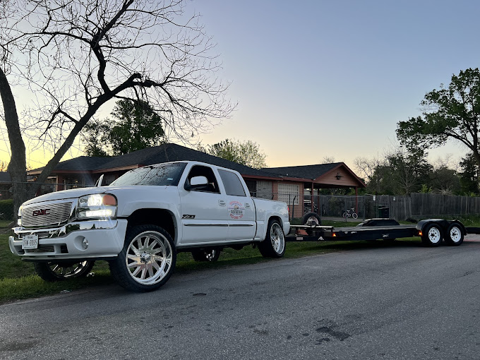 A white truck pulling a trailer down a street