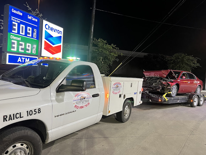 A white tow truck towing a red truck