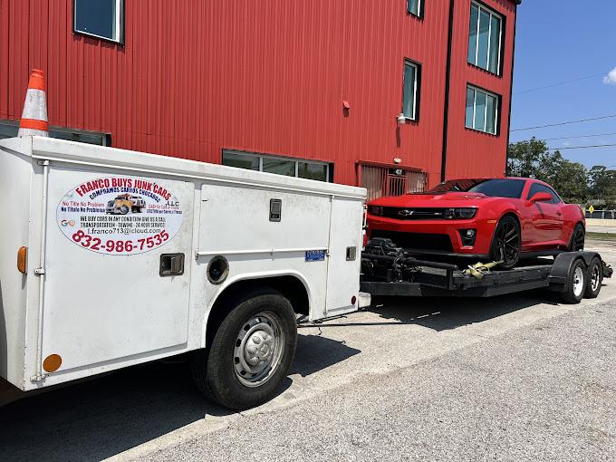 A white truck with a red car on the back of it