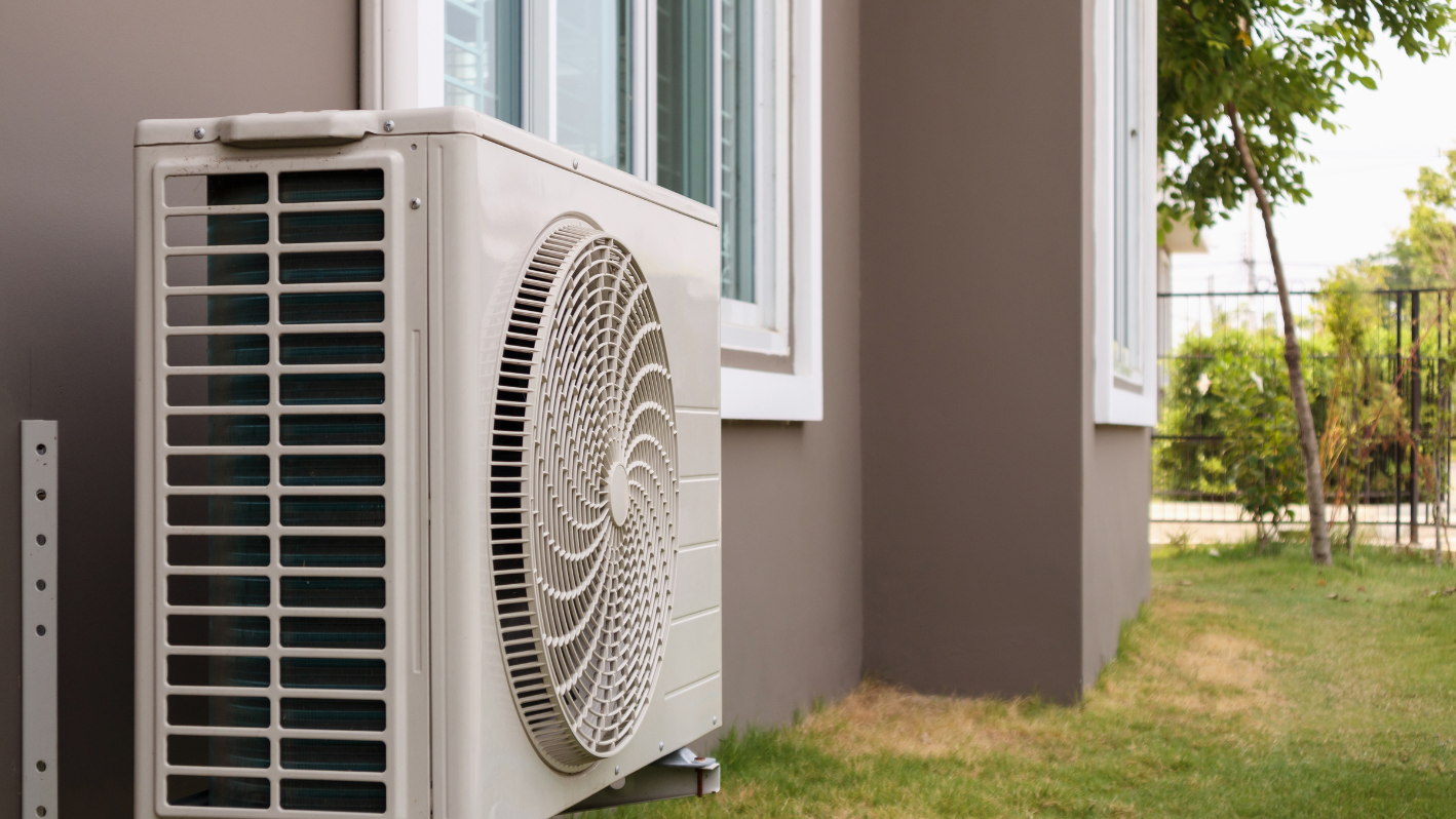 A white air conditioner sitting on the side of a building